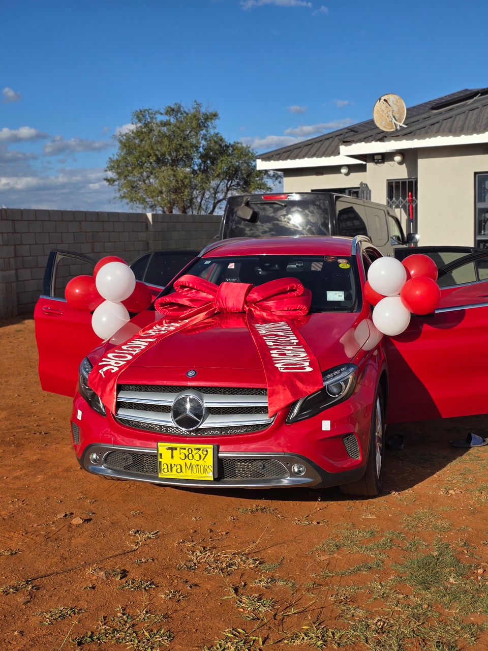 Red Mercedes-Benz GLA with red Lara Motors ribbon and balloons