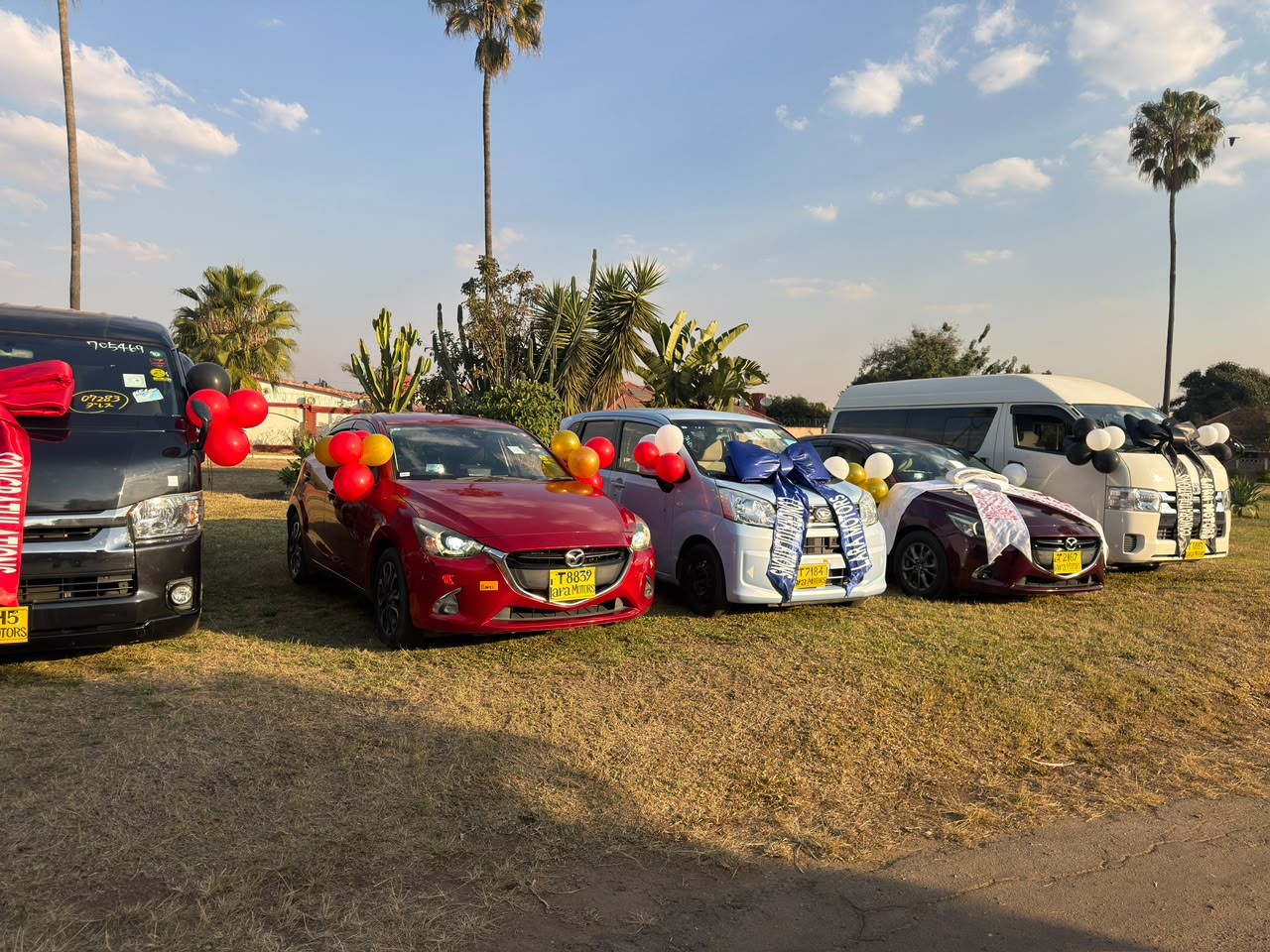 Lara Motors delivery lineup of Mazda, Toyota and Hiace vehicles with ribbons and balloons