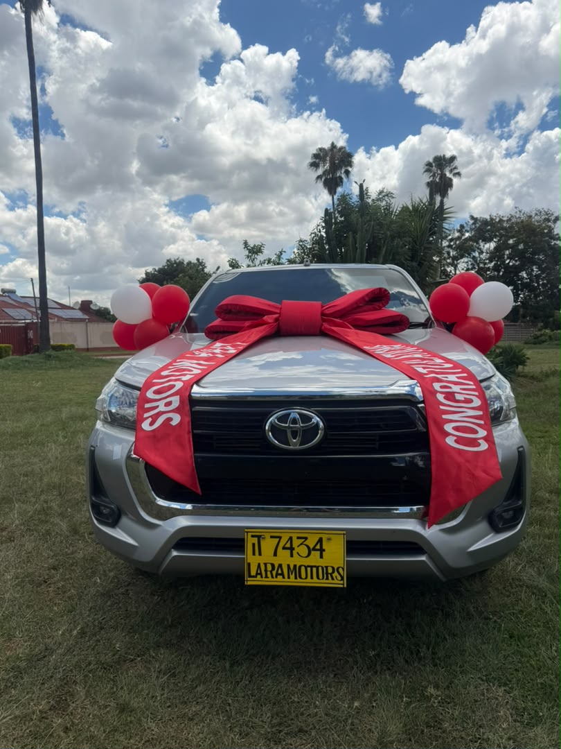 Silver Toyota Hilux with red ribbon and red and white balloons