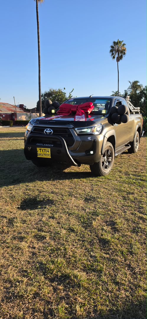 Bronze Toyota Hilux extra cab with red bow and black balloons