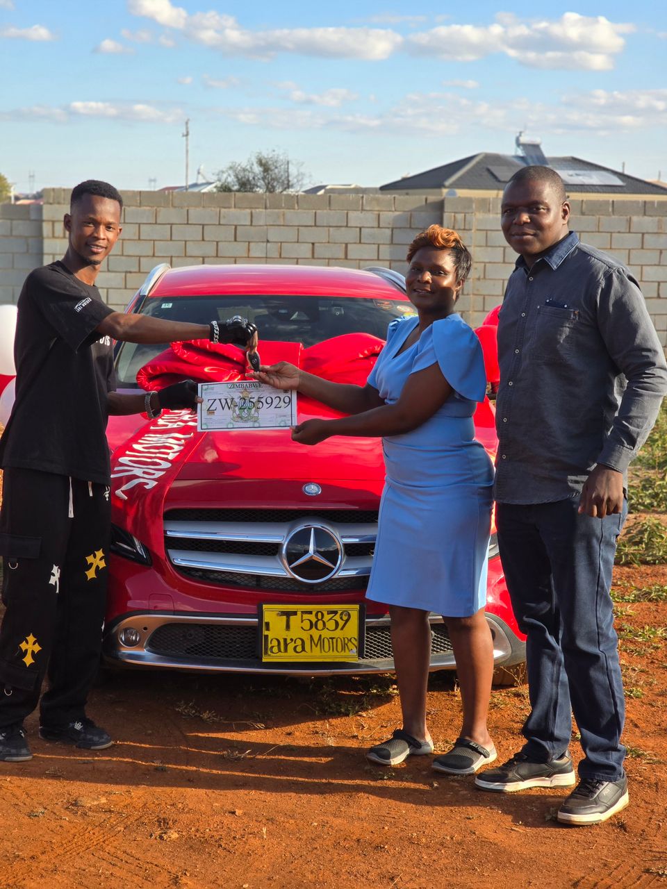 Customer receiving keys and registration book for a red Mercedes-Benz GLA