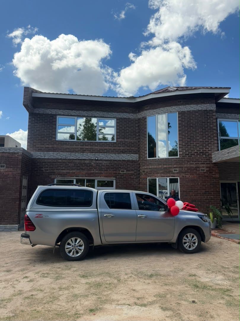 Silver Toyota Hilux double cab with canopy and red ribbon at a home
