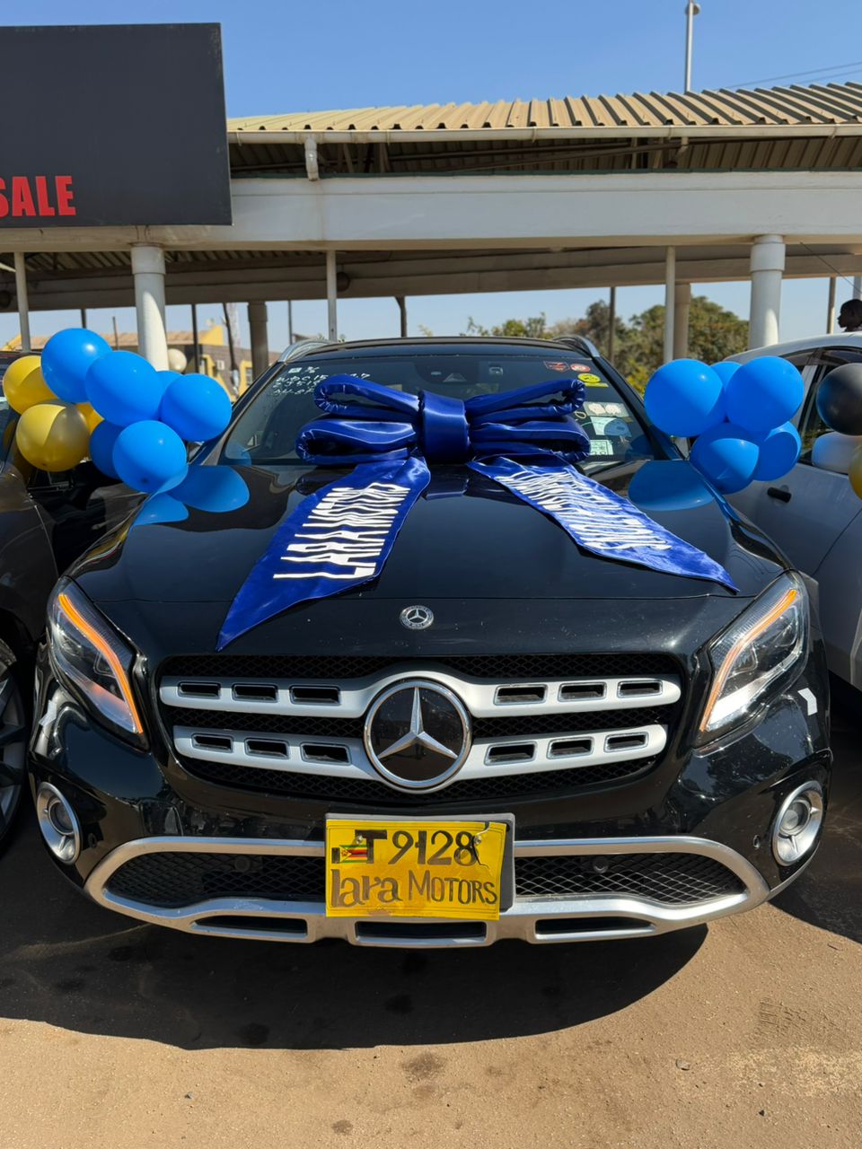 Black Mercedes-Benz GLA with blue Lara Motors congratulations ribbon and balloons